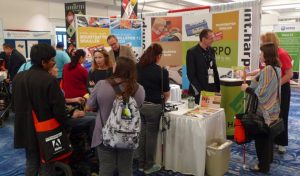 En grupp människor står vid en stånd på CSUN och tittar på och diskuterar något som presenteras,