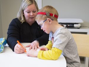 Emelie i svart tröja och ljust axelllångt hår till vänser och Moltas med glasögon och grå skjorta ritar,