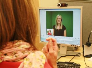 den teckenspråkiga kommunicerar med tolken som syns i datorn