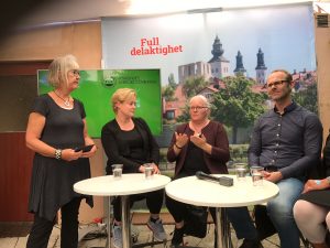 Liindas tolk MM, Linda och Klas Nelfelt sitter vid vita bord på scenen i Almedalen. Anne står upp.