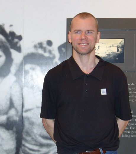 Richard Sahlin i kortärmad svart skjota, står framför en utställningsskärm