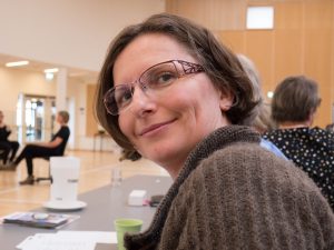 Porträtt Marina med kort brunt hår, glasögon, brun kofta.