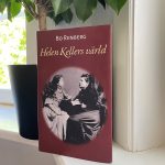 Bo Renbergs bok "Helen Kellers värld" som står på en fönsterbräda framför en blomkruka med en grön växt. Foto.