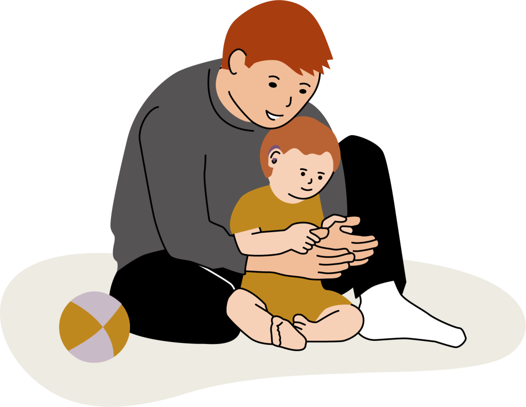 En man sitter på golvet med ett barn framför sig. Mannen håller sina händer framför sig och barnet har tagit tag i mannens tummar med sina händer.